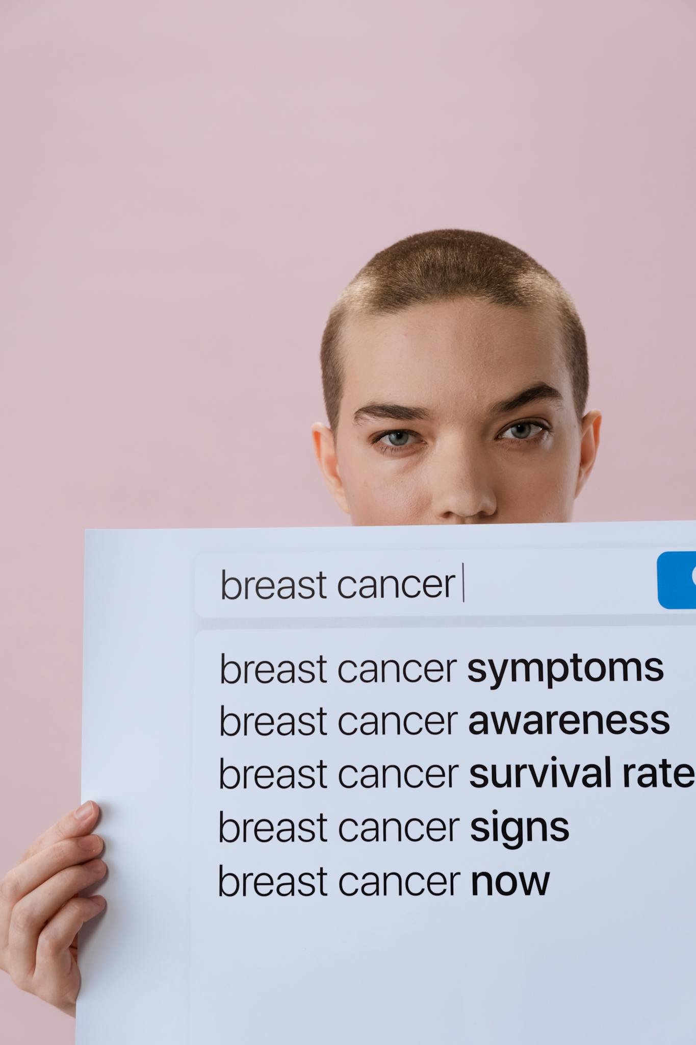 Woman holding a sign on breast cancer awareness with a serious expression.